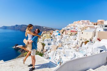 Young couple looks down on the landscape of the island of Santorini